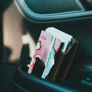 Canadian $50 bill in a wallet money clip in a car's cup holder.