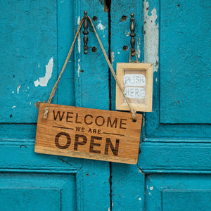 Welcome We Are Open sign on a blue door.