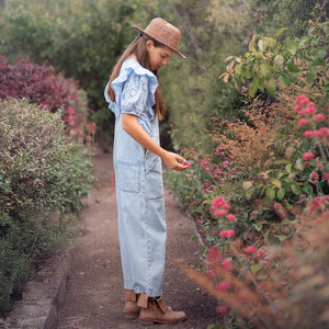 Girl in denim overalls exploring a garden filled with colourful flowers, embodying the spirit of adventure and discovery, relevant to Mystery Day Trips' curated experiences in Ontario.