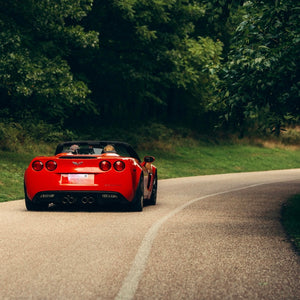 Red convertible sports car driving along a winding road in Ontario, representing adventure and exploration for Mystery Day Trips.