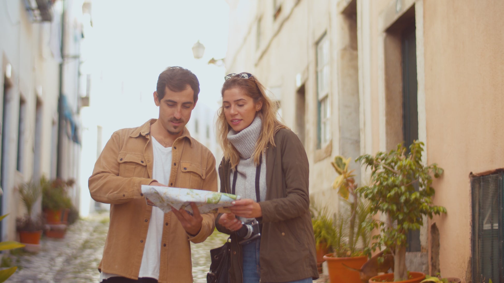 Couple exploring a map in a charming street, highlighting adventure and discovery, relevant to Mystery Day Trips in Ontario.