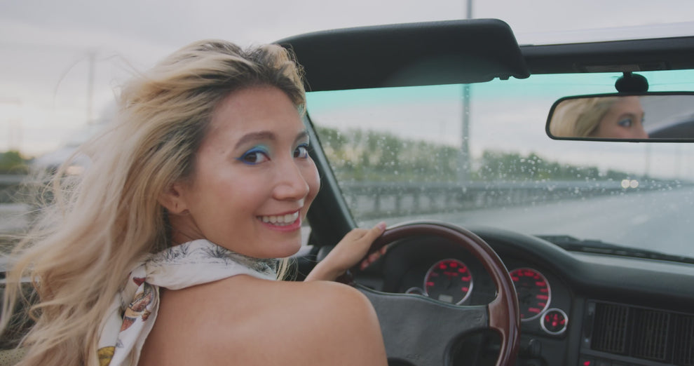 Woman driving a convertible with a joyful expression, showcasing a spontaneous adventure on an open road, reflecting the essence of Mystery Day Trips in Ontario.
