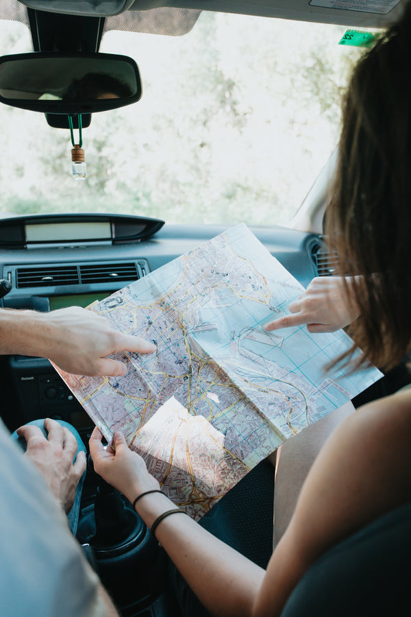 A couple in a car holding a map.