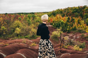 Woman in skirt overlooking a landscape as a solo traveller.
